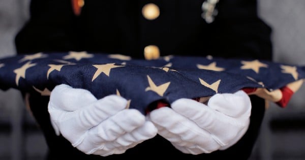 soldier holding folding U.S. flag at military funeral