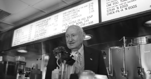 Truett Cathy in front of the menu of the first Chick-Fil-A menus