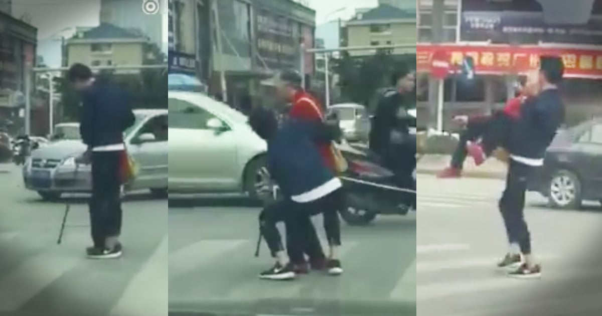 Young Man Carries Elderly Woman Across Busy Intersection